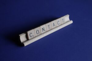A horizontal line of scrabble letters that spell contact.