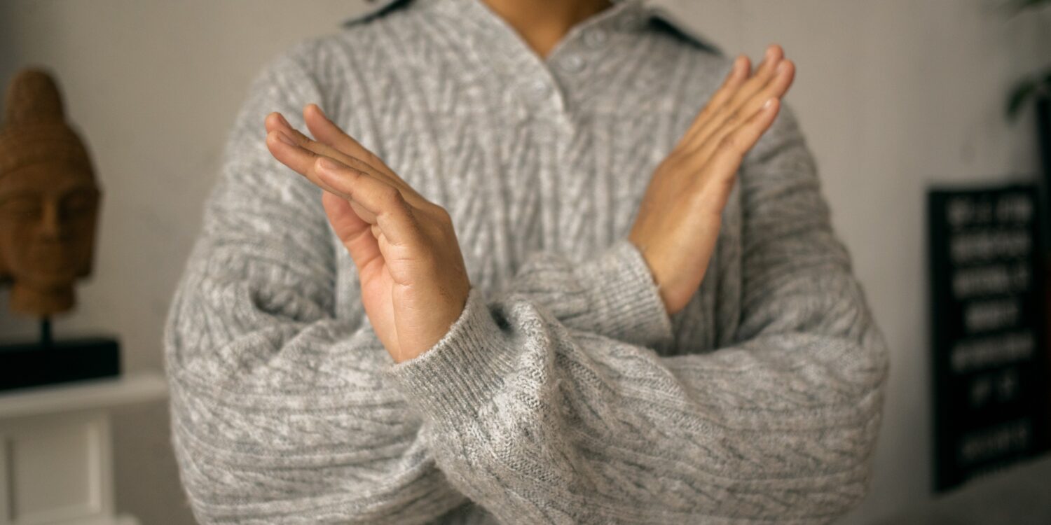 A woman wearing a sweater crosses her arms in front of her chest.