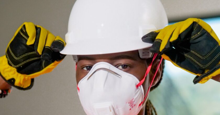 Person wearing respirator mask and white hardhat