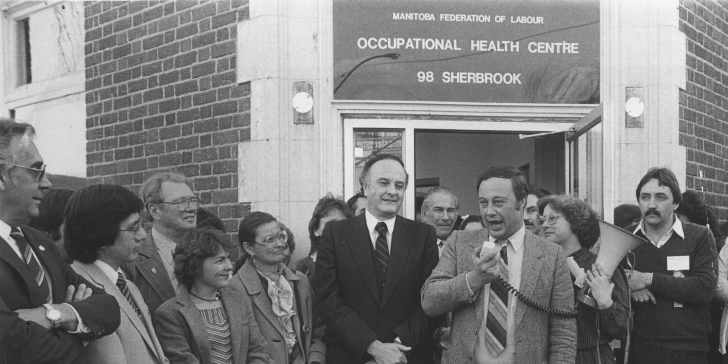 MFL President Dick Martin speaks at the opening of the MFL Occupational Health Centre in 1983, as Premier Howard Pawley, Executive Director Lissa Donner, and a crowd of supporters look on.