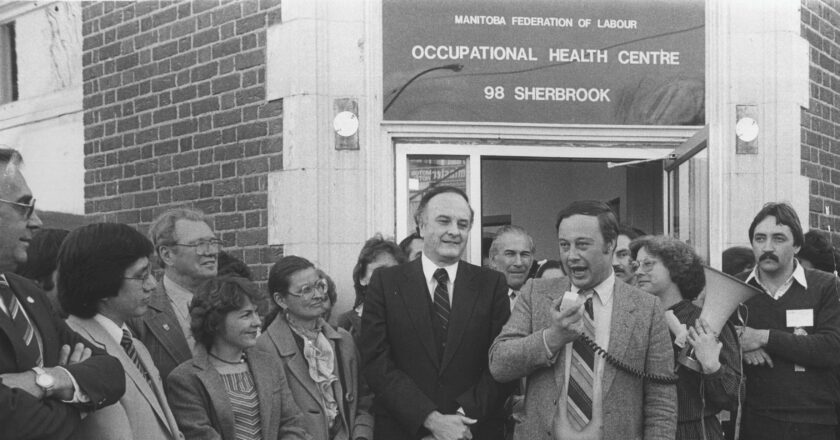 MFL President Dick Martin speaks at the opening of the MFL Occupational Health Centre in 1983, as Premier Howard Pawley, Executive Director Lissa Donner, and a crowd of supporters look on.